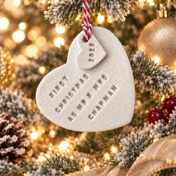 Personalised white clay double heart Christmas ornament stamped with First Christmas as Mr and Mrs Chapman 2026 hanging on a festive Christmas tree