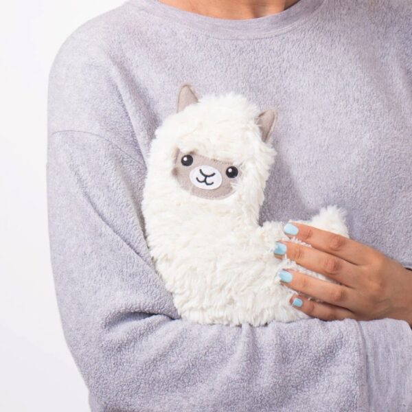 A woman holding a white, fluffy, microwaveable llama-shaped lap warmer.