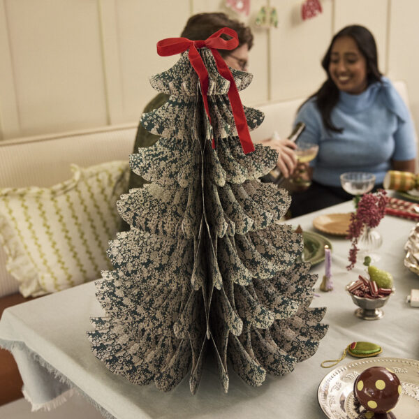 Giant green Liberty print paper honeycomb tree with a red velvet bow on a festive dining table