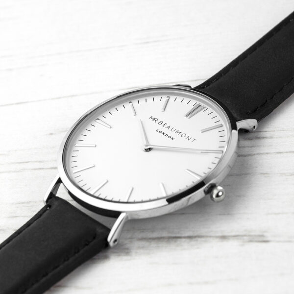 A Mr Beaumont London modern vintage watch with a white face, polished silver-tone casing, and black leather strap resting on a white book.