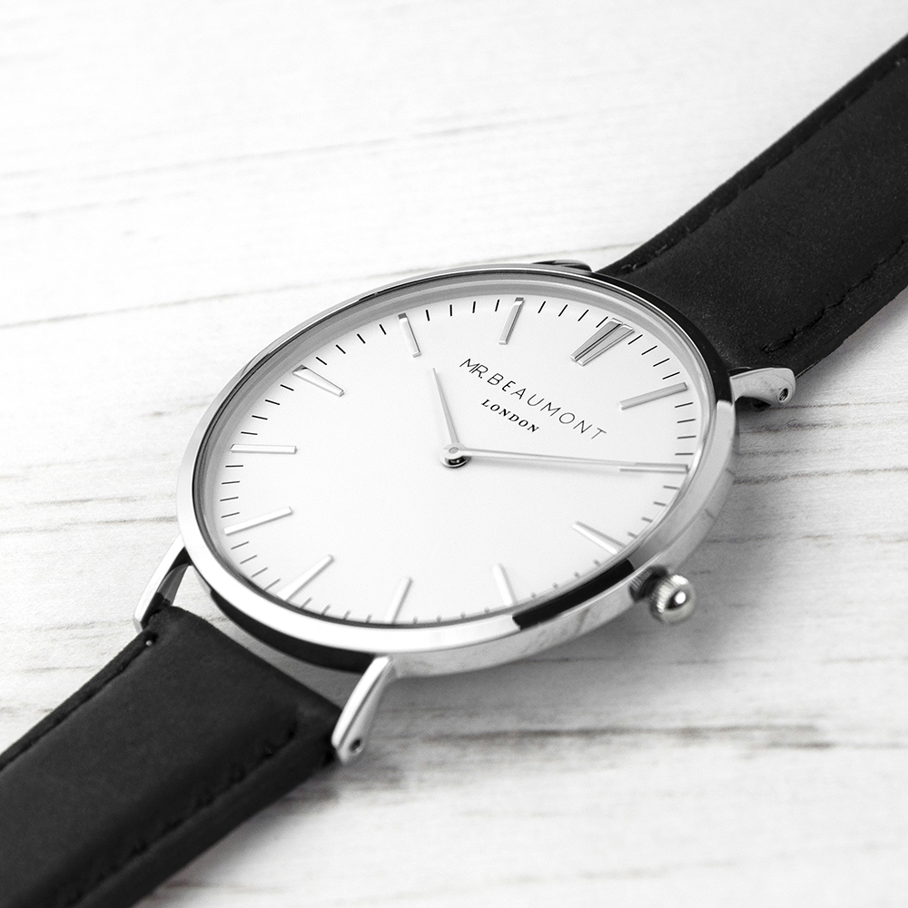 A Mr Beaumont London modern vintage watch with a white face, polished silver-tone casing, and black leather strap resting on a white book.
