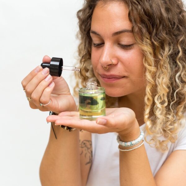 Woman holding Morning Vibe Daily Aromatherapy Mood Oil bottle and pipette up to inhale the aroma by Abode Home & Gifts
