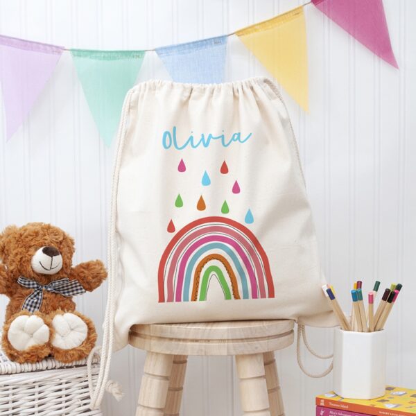 Personalised natural canvas children's PE kit drawstring bag featuring a colourful rainbow print and the name Olivia.