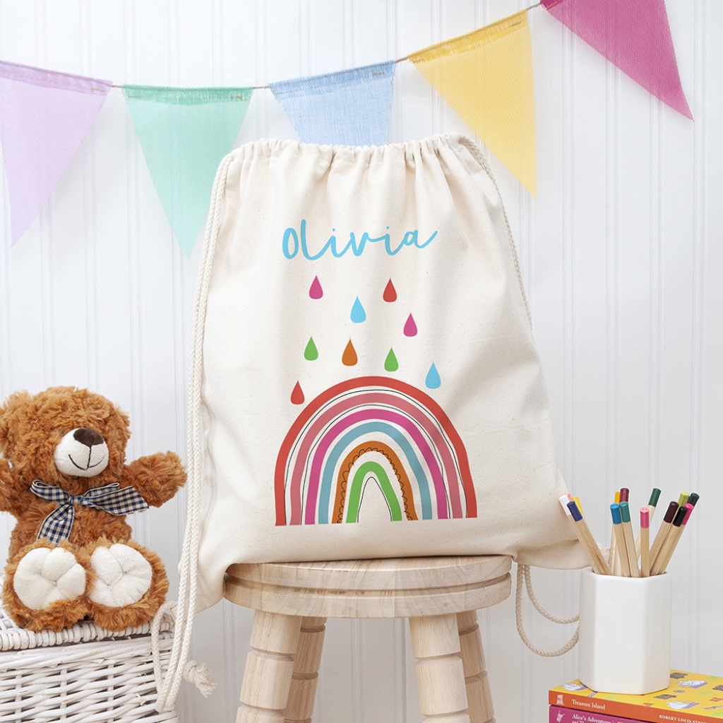 Personalised natural canvas children's PE kit drawstring bag featuring a colourful rainbow print and the name Olivia.