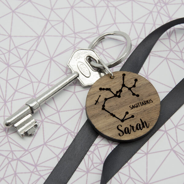 Personalised round walnut wooden zodiac keyring engraved with Sagittarius star sign constellation and the name Sarah.