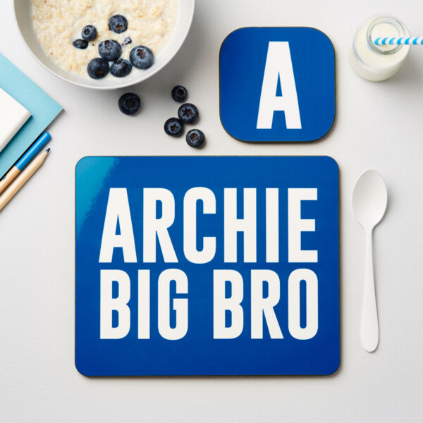 Boy's personalised blue bro placemat printed with Archie Big Bro next to a matching initial A coaster and breakfast bowl
