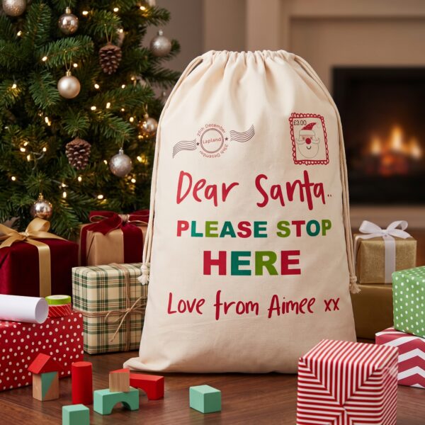 Personalised Dear Santa Christmas sack custom printed with Love from Aimee xx placed next to a Christmas tree and gifts