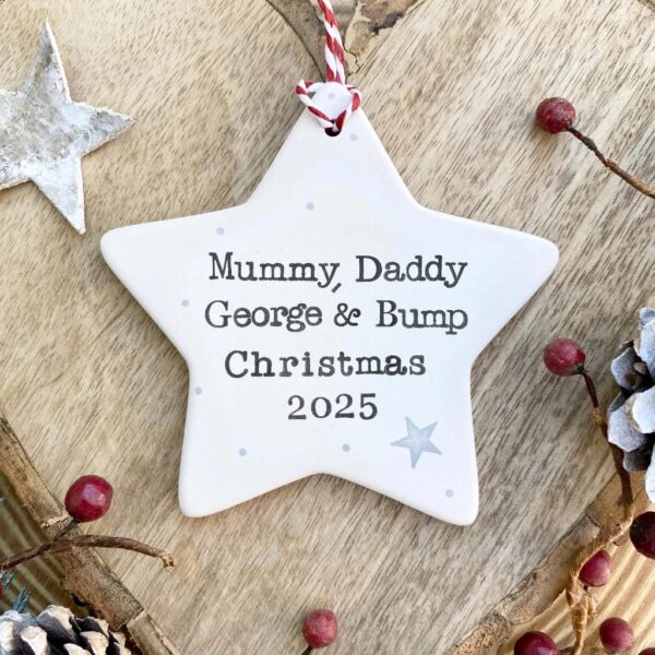 Personalised white ceramic Christmas star ornament stamped with Mummy Daddy Ella and Mila Christmas 2025 and a gold snowflake.