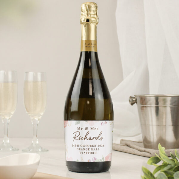 Personalised floral watercolour bottle of Prosecco printed with Mr & Mrs Richards 14th October 2024 beside champagne flutes