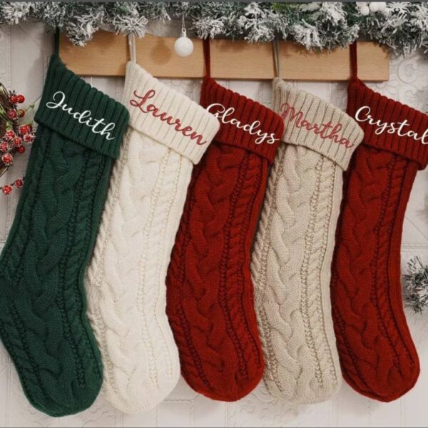 Five personalised knitted Christmas stockings hanging from a mantelpiece