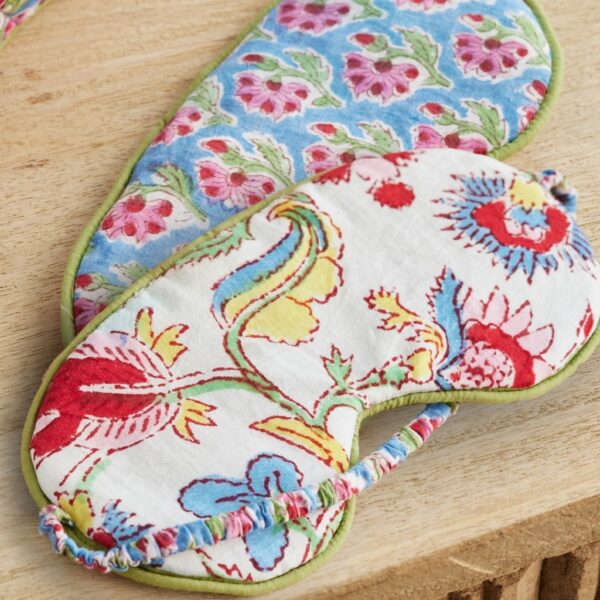 Two reversible block print eye masks showing a blue floral side and a white side with bright red and blue flowers.