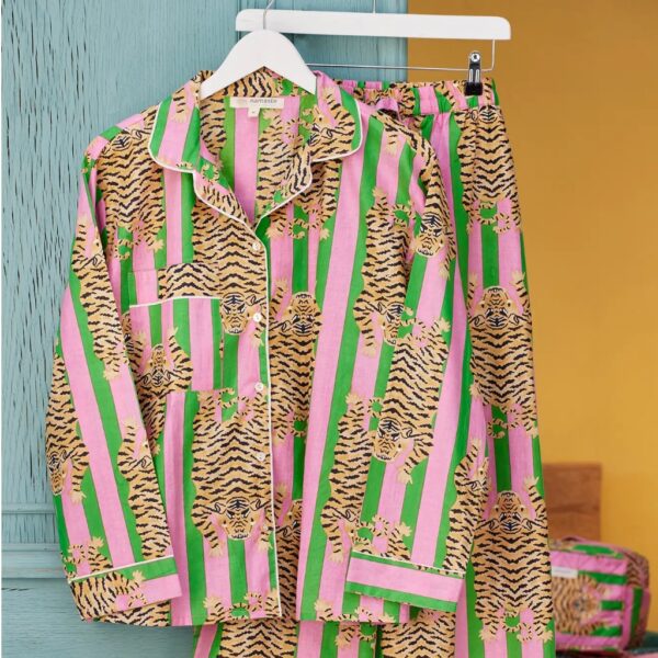 Pink and green tiger stripe cotton pyjamas with white piping hanging against a blue painted door